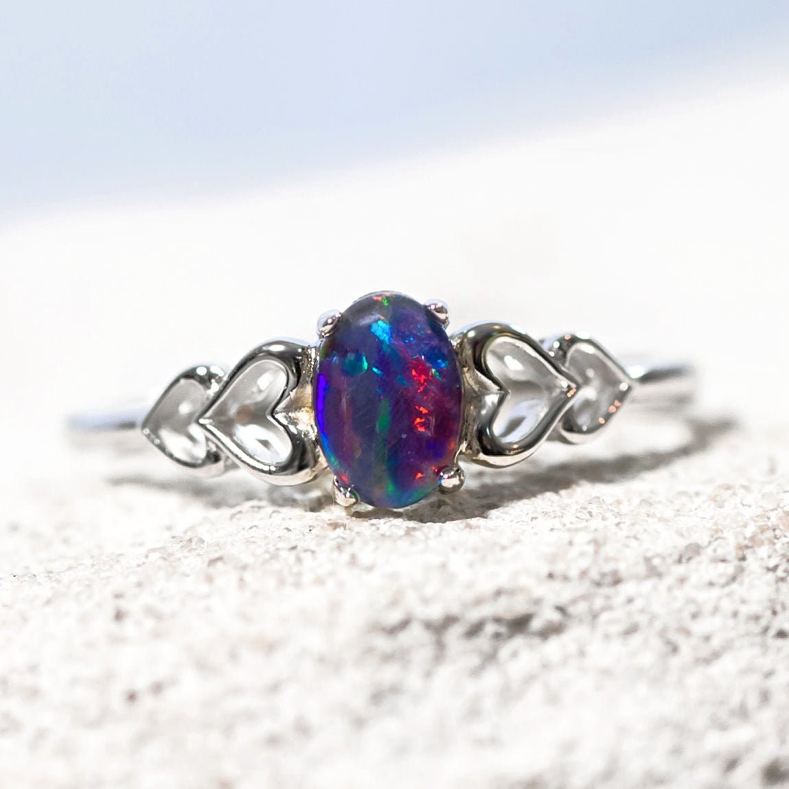 Silver ring with a colorful gemstone on a textured surface