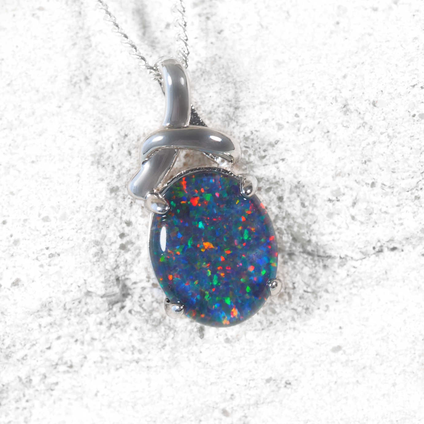 Multi-colour opal pendant with silver setting on a white background