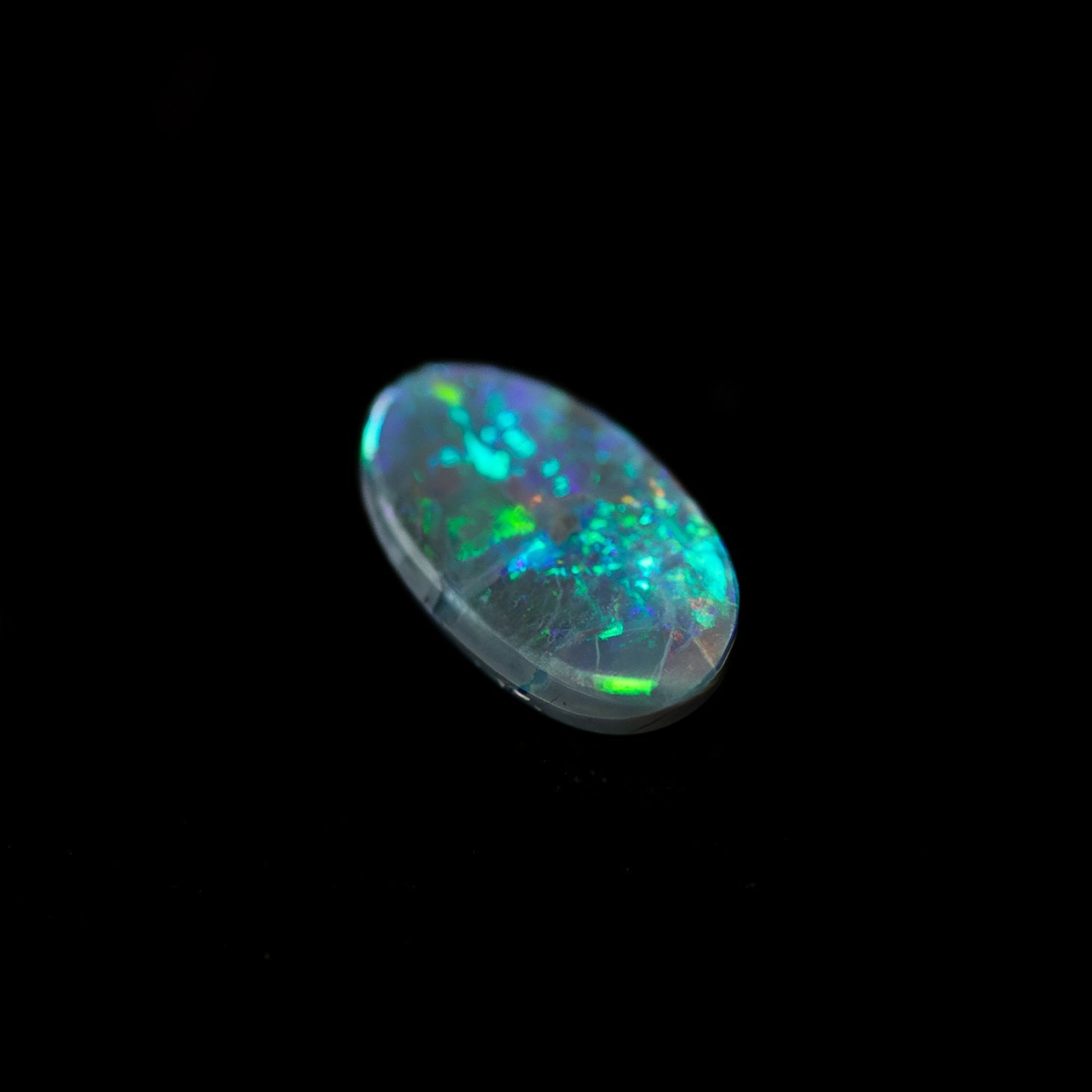 Solid black opal gemstone featuring bright green play-of-colour