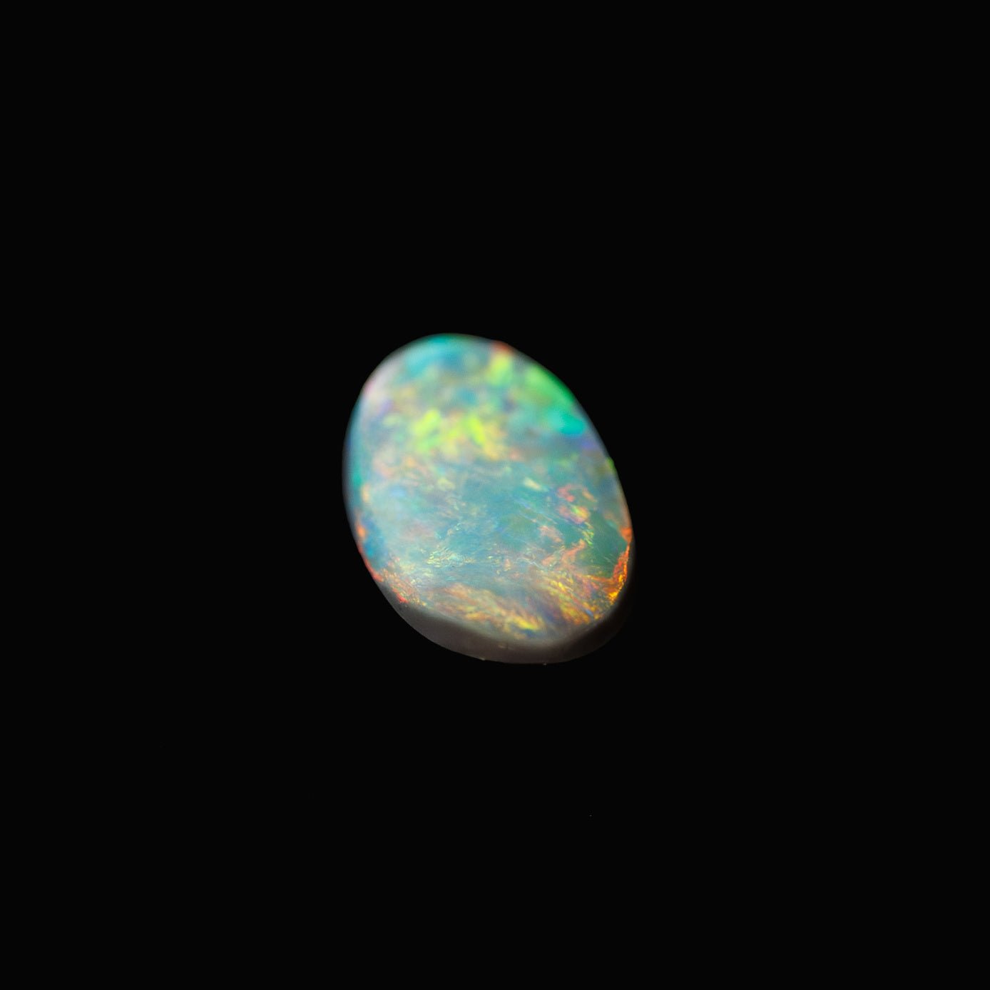Close-up of Australian black opal showing brilliant flashes of red and gold on a deep body tone