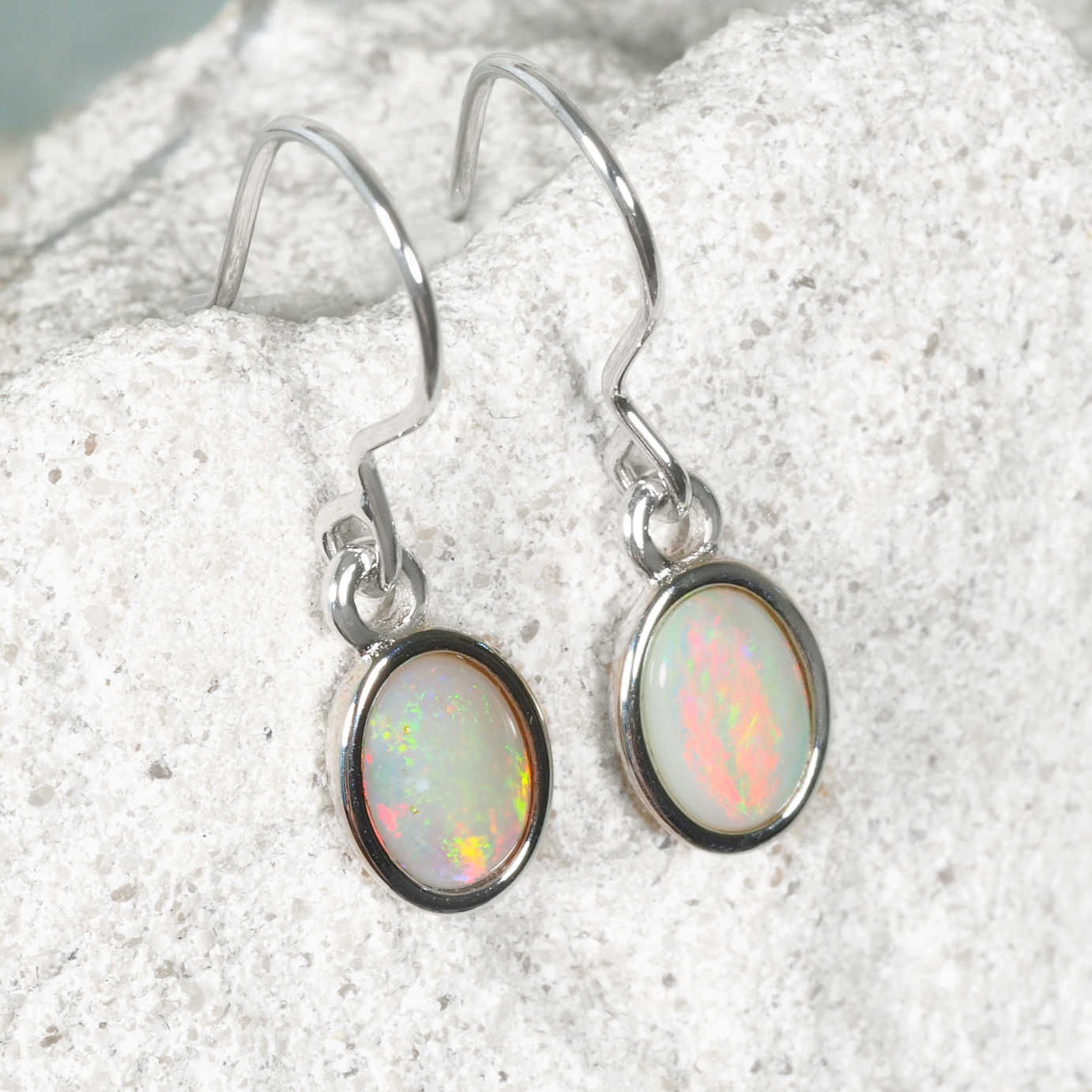 Opal earrings on a sandy background