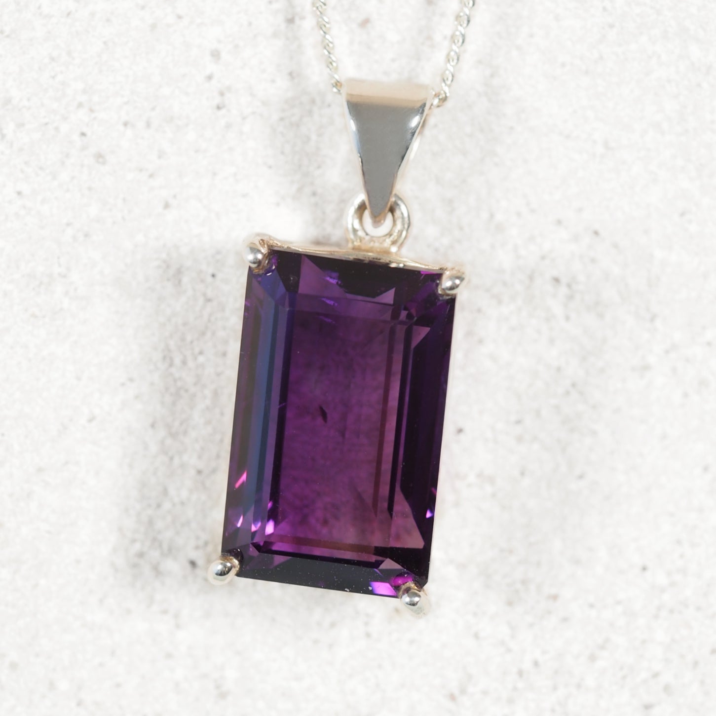 Faceted square Amethyst pendant in a polished silver claw setting, highlighting deep purple hues