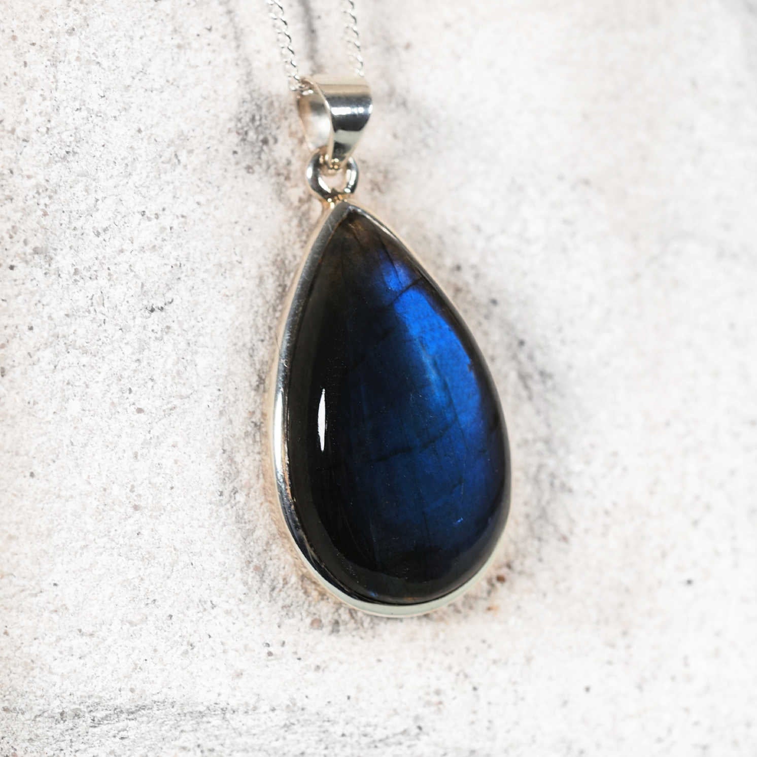 Teardrop-shaped blue labradorite gemstone pendant on a silver chain 