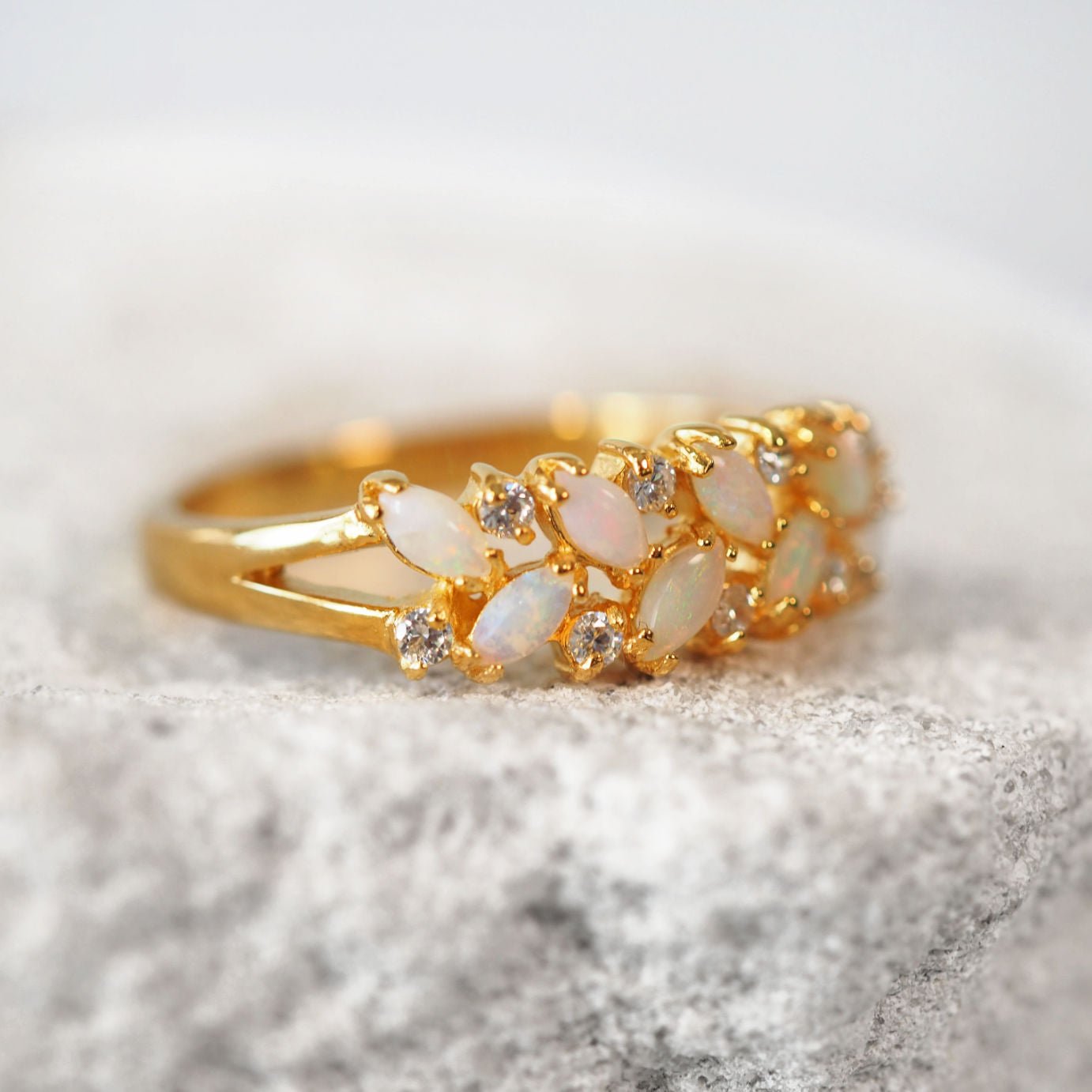 Gold ring with opal stones on a textured surface