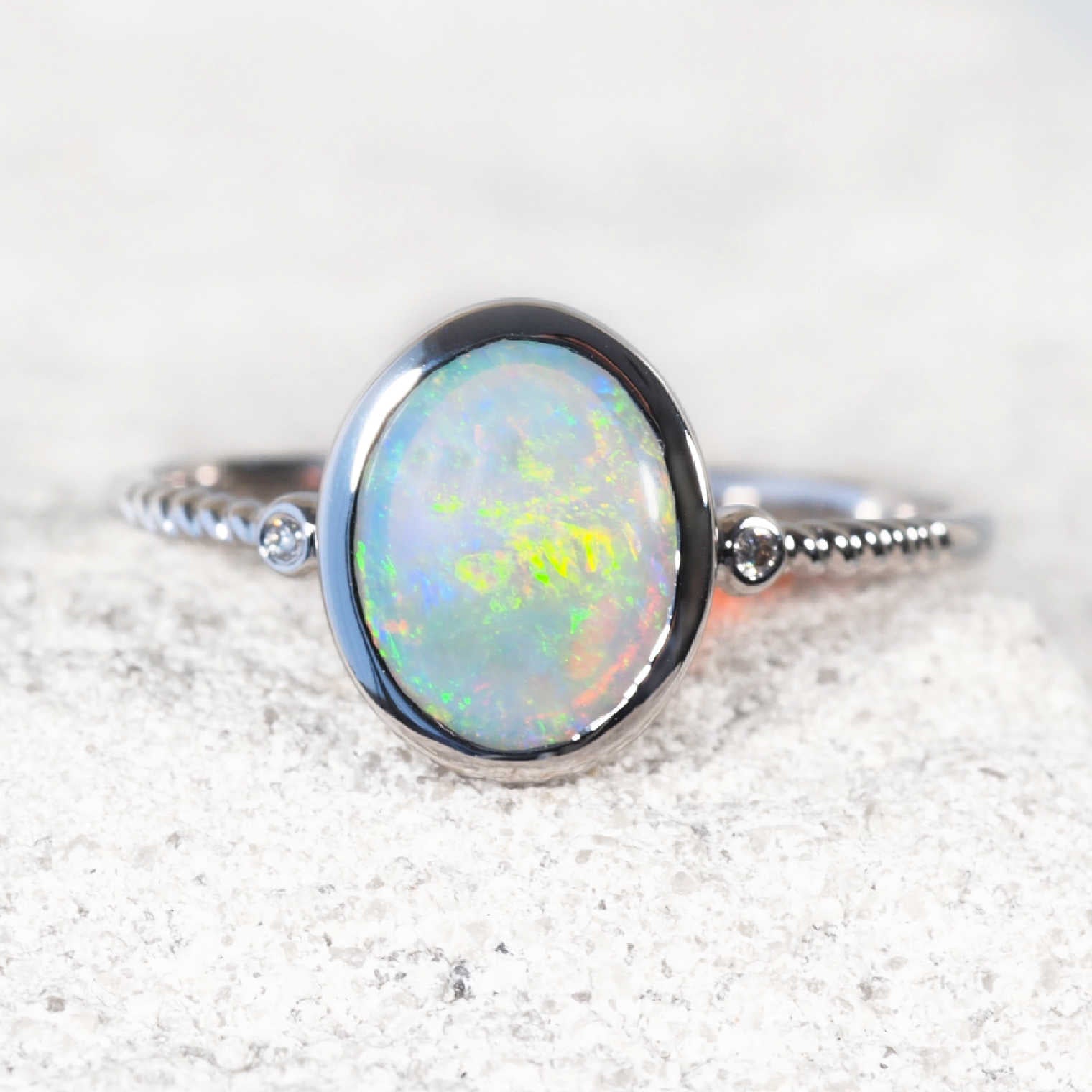 Genuine Opal ring with white gold setting on a textured white surface