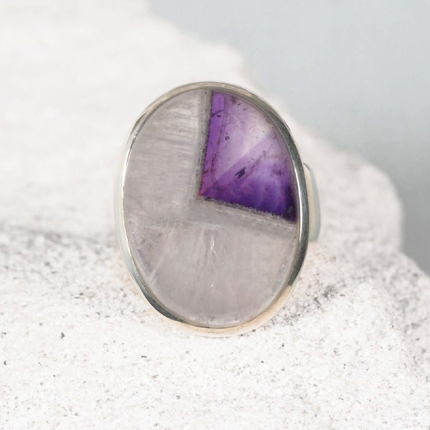 Silver bezel-set amethyst ring  featuring a smooth round amethyst cabochon with clear and purple tones.