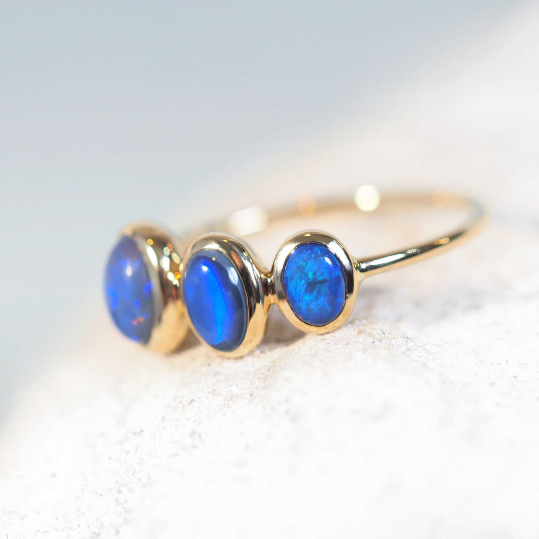 blue opal ring set with three black opals in gold