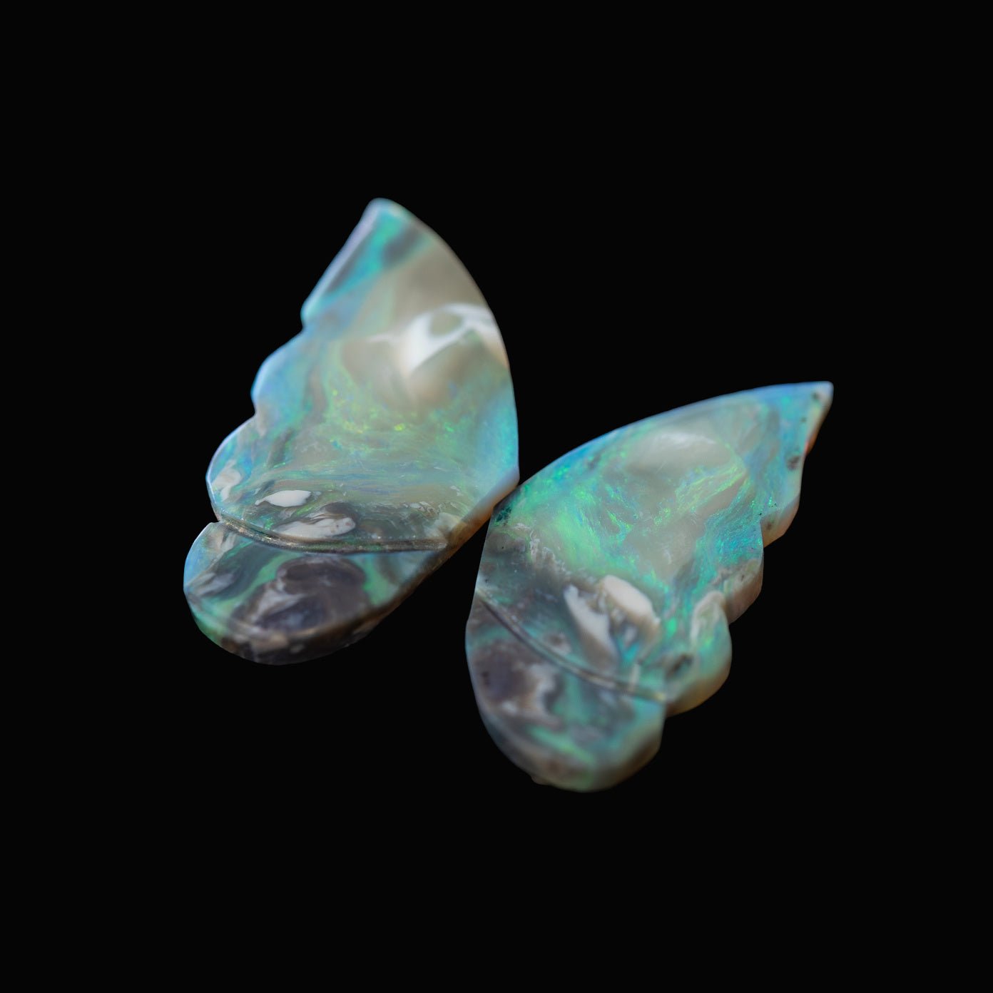 Two Lightning Ridge opal stones with a butterfly design on a black background