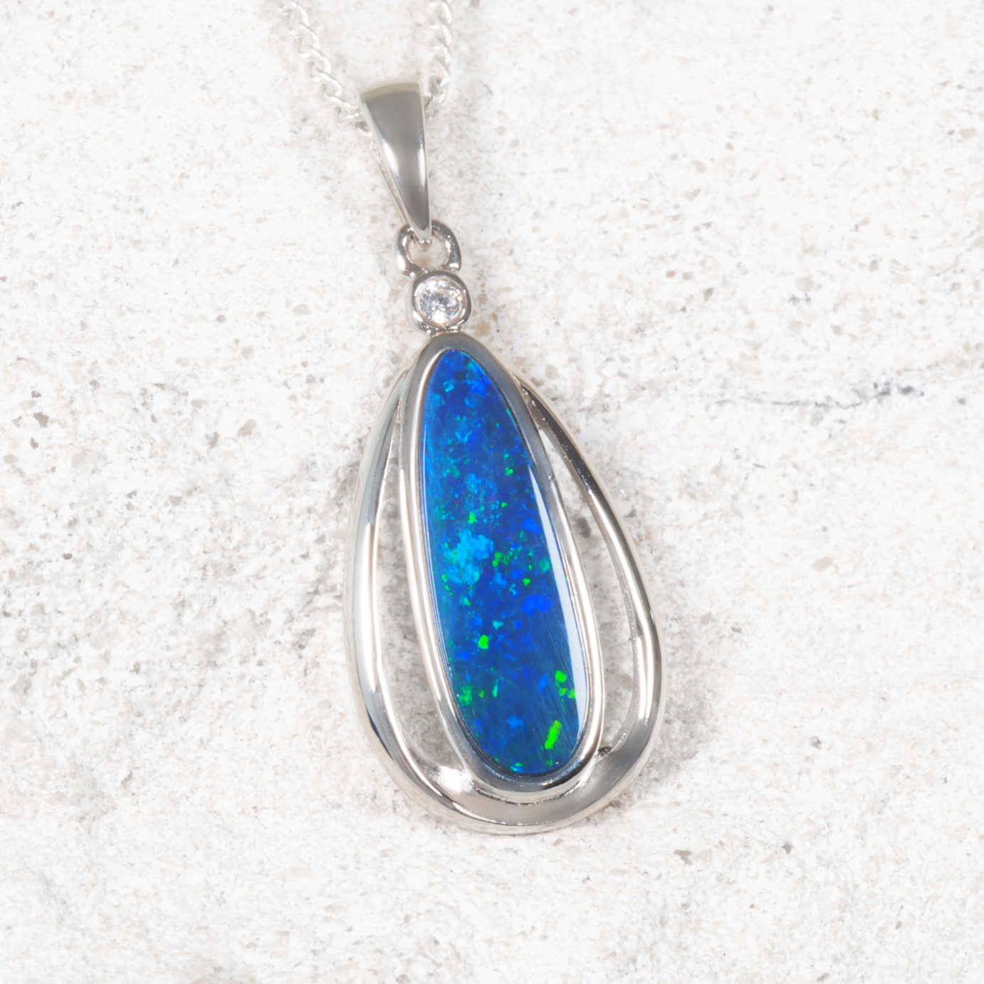Opal pendant with silver setting on a textured white background
