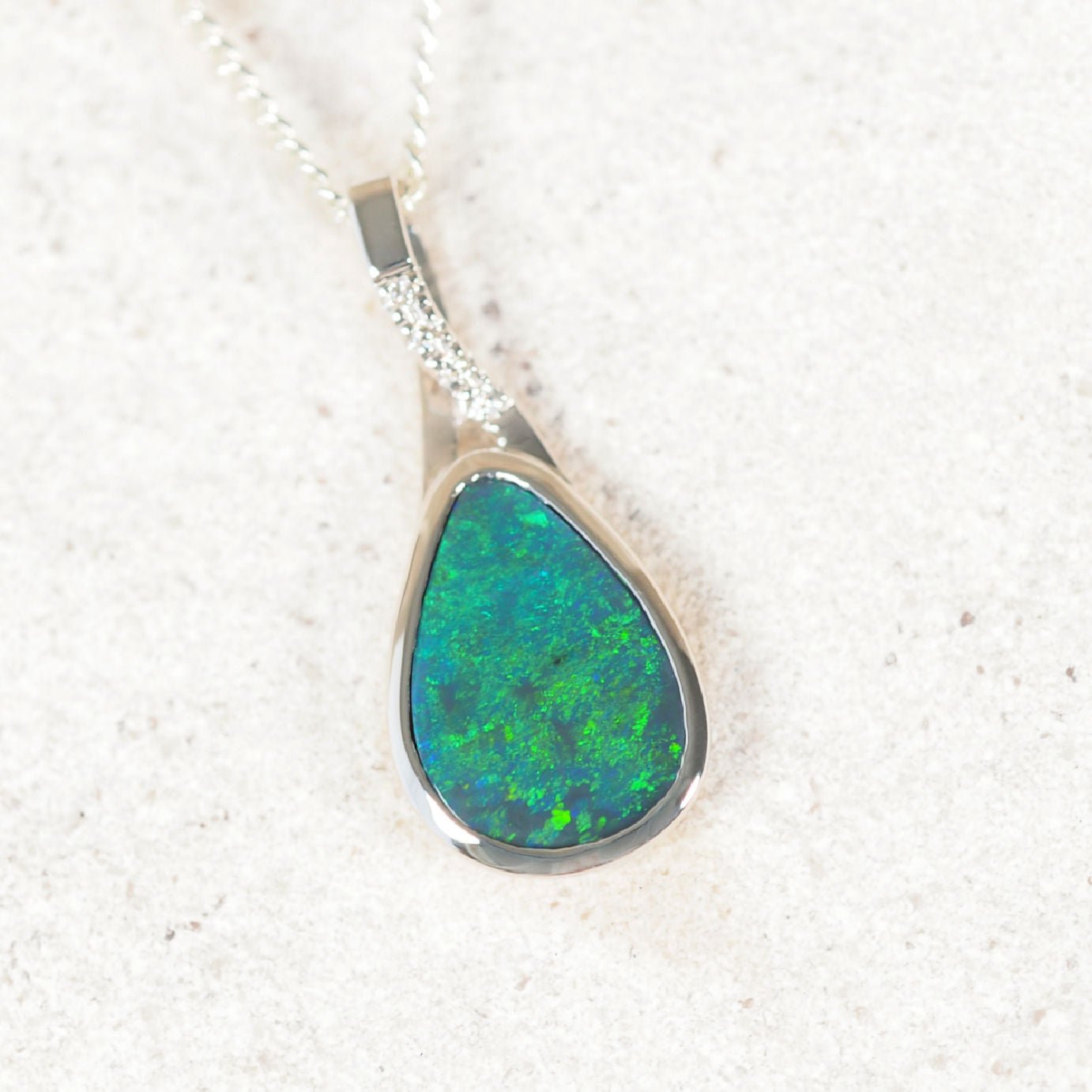 Elegant 14ct white gold necklace showcasing a teardrop black opal with vibrant green flashes and four sparkling diamonds