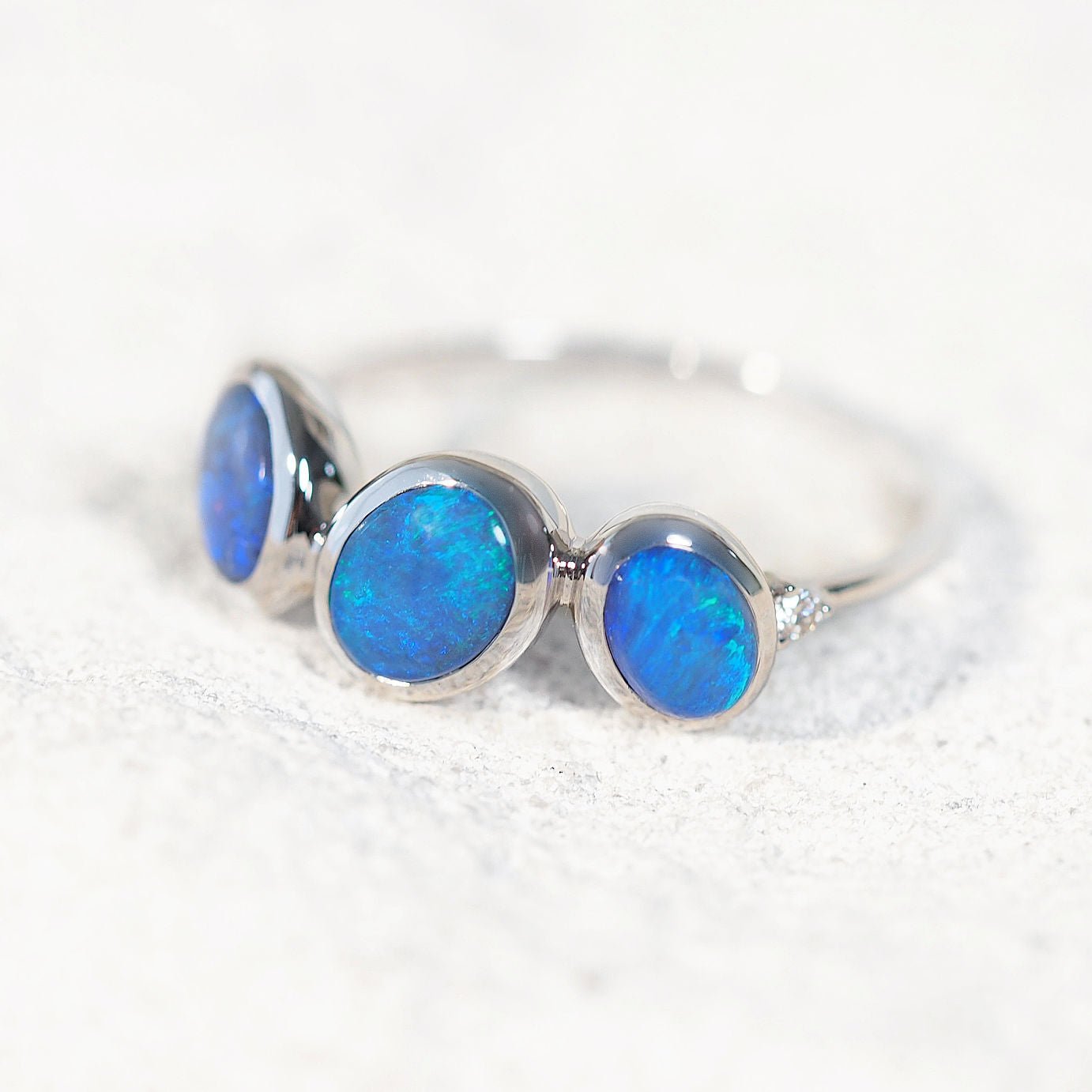 Australian White gold ring with three blue opal stones on a white background