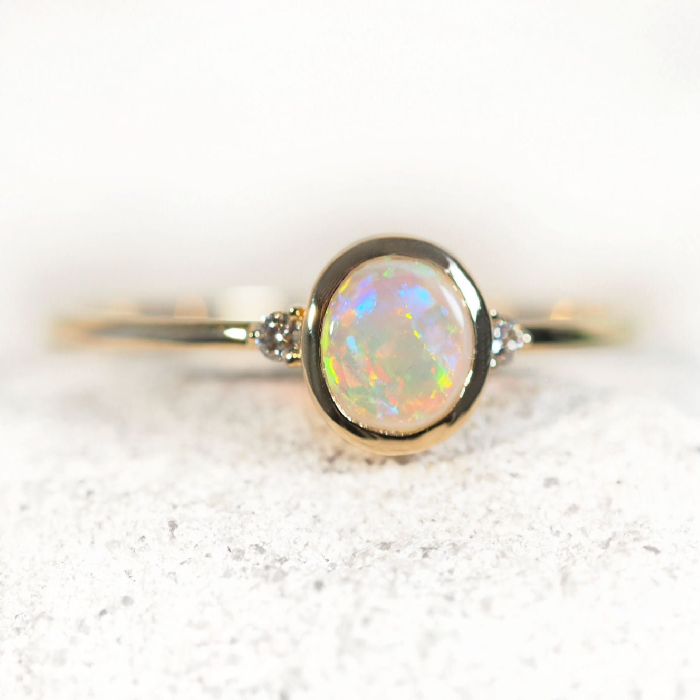 Gold ring with a central opal stone on a white background