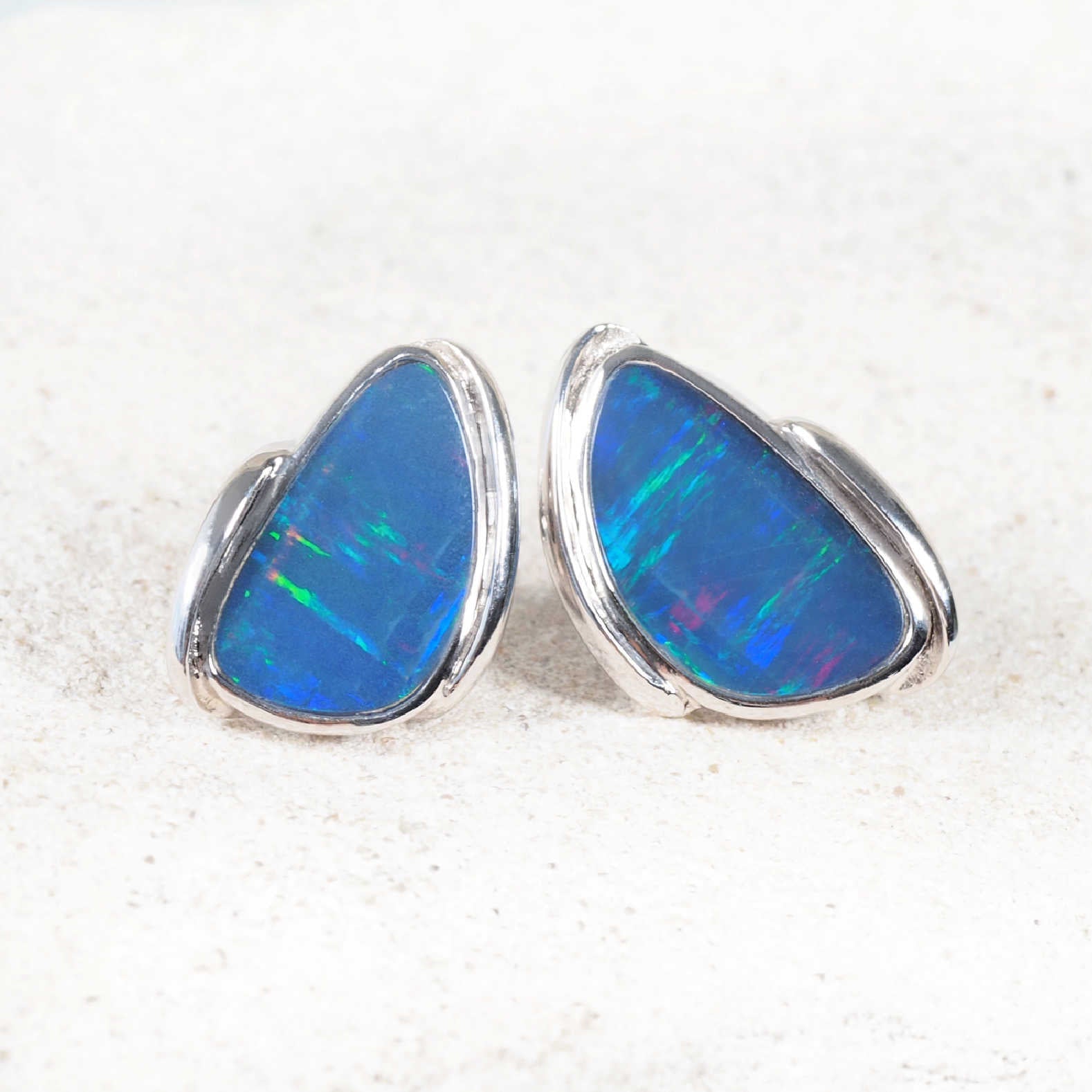 Close-up of Australian doublet opal earrings featuring bezel-set triangle stones