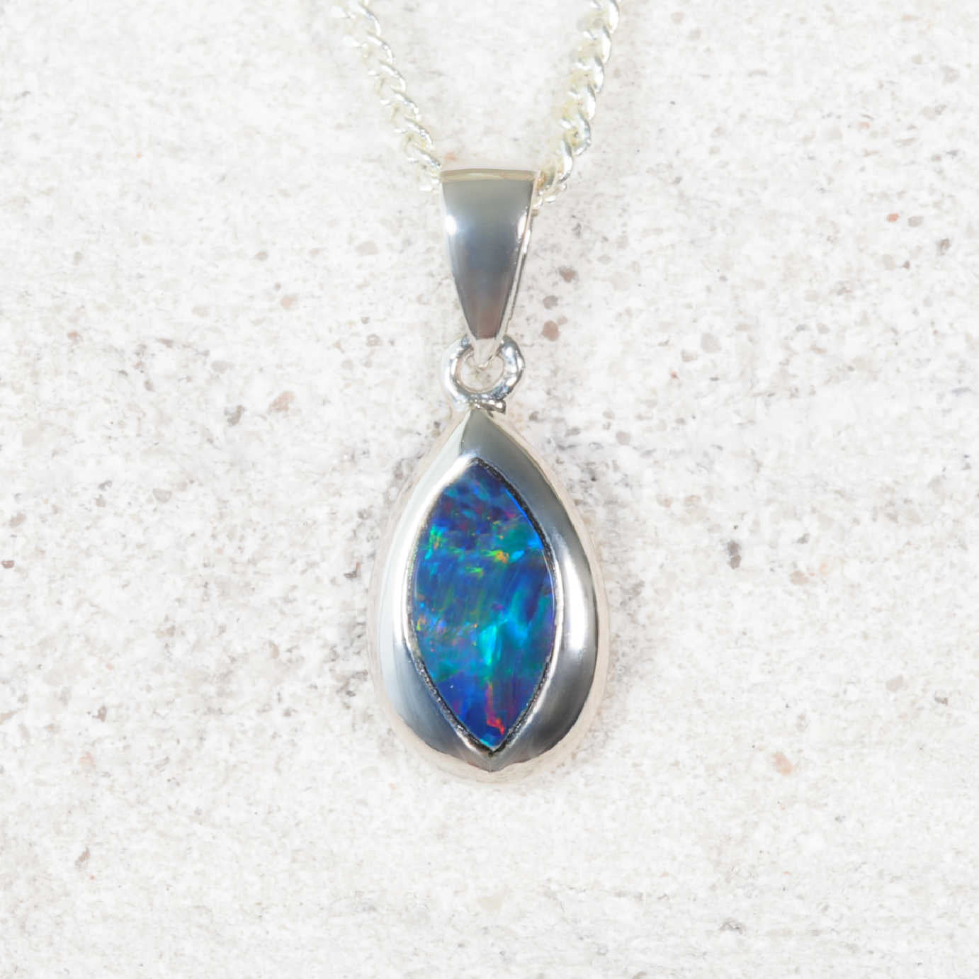 Opal pendant necklace on a textured white background