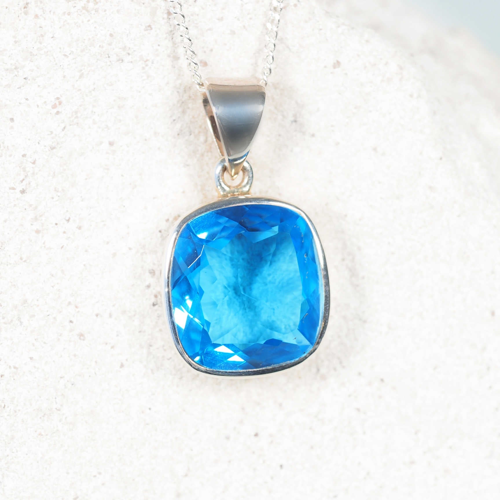 The 'Celeste' square Light Blue Topaz pendant in silver bezel, showing soft icy-blue gemstone with faceted sparkle