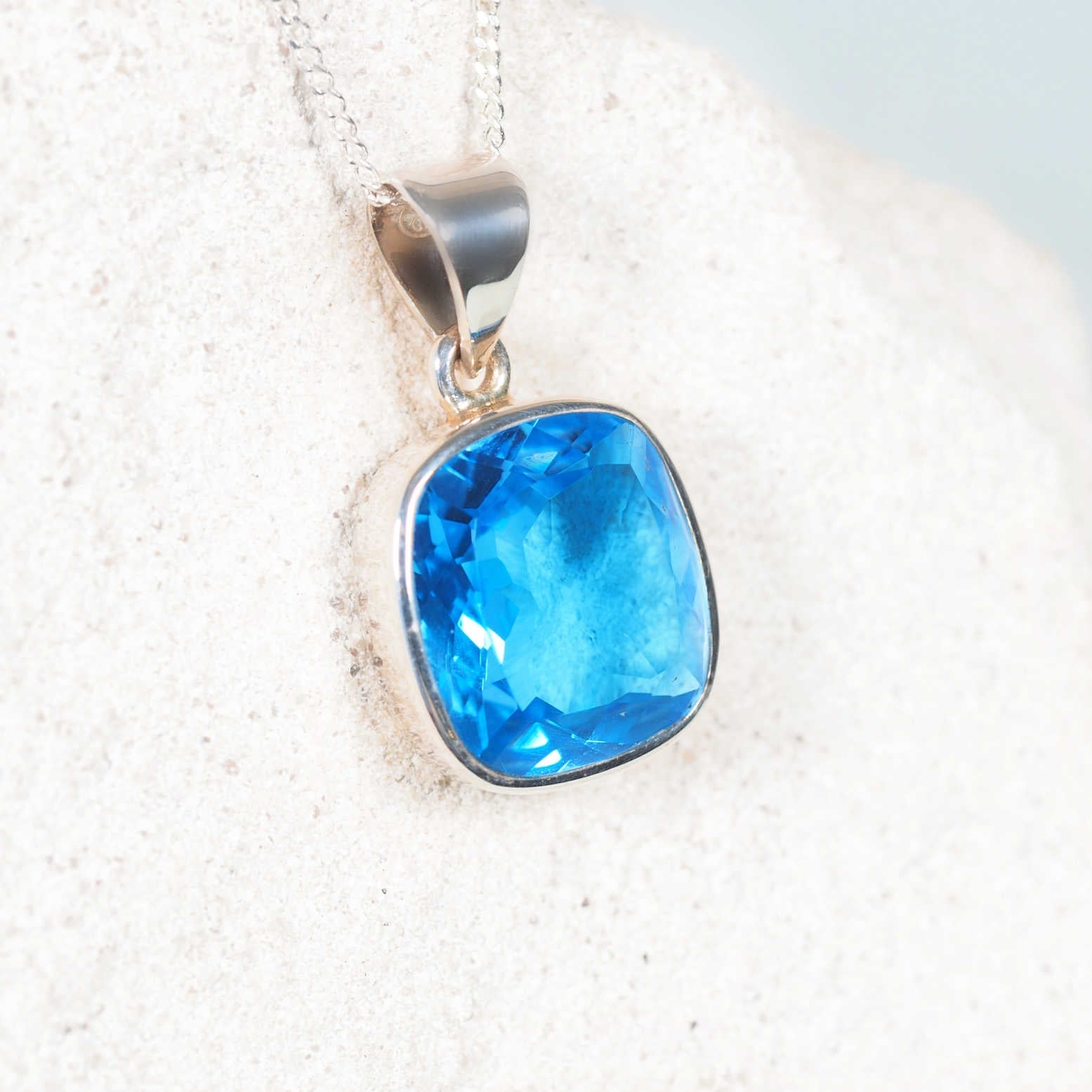 Close-up of The 'Celeste' pendant highlighting faceted light Blue Topaz set in polished silver bezel