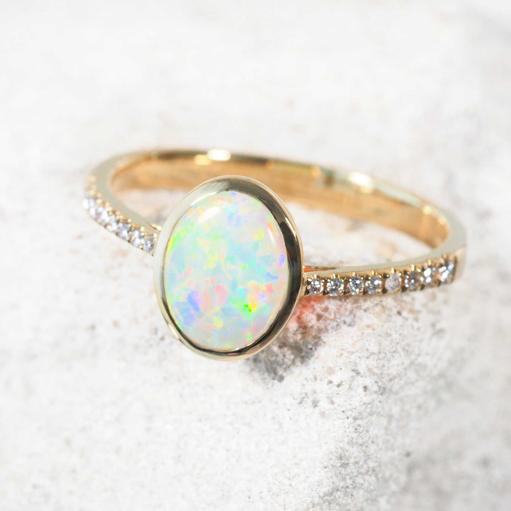 Celeste ring on hand, showcasing vivid opal colour and sparkling diamonds