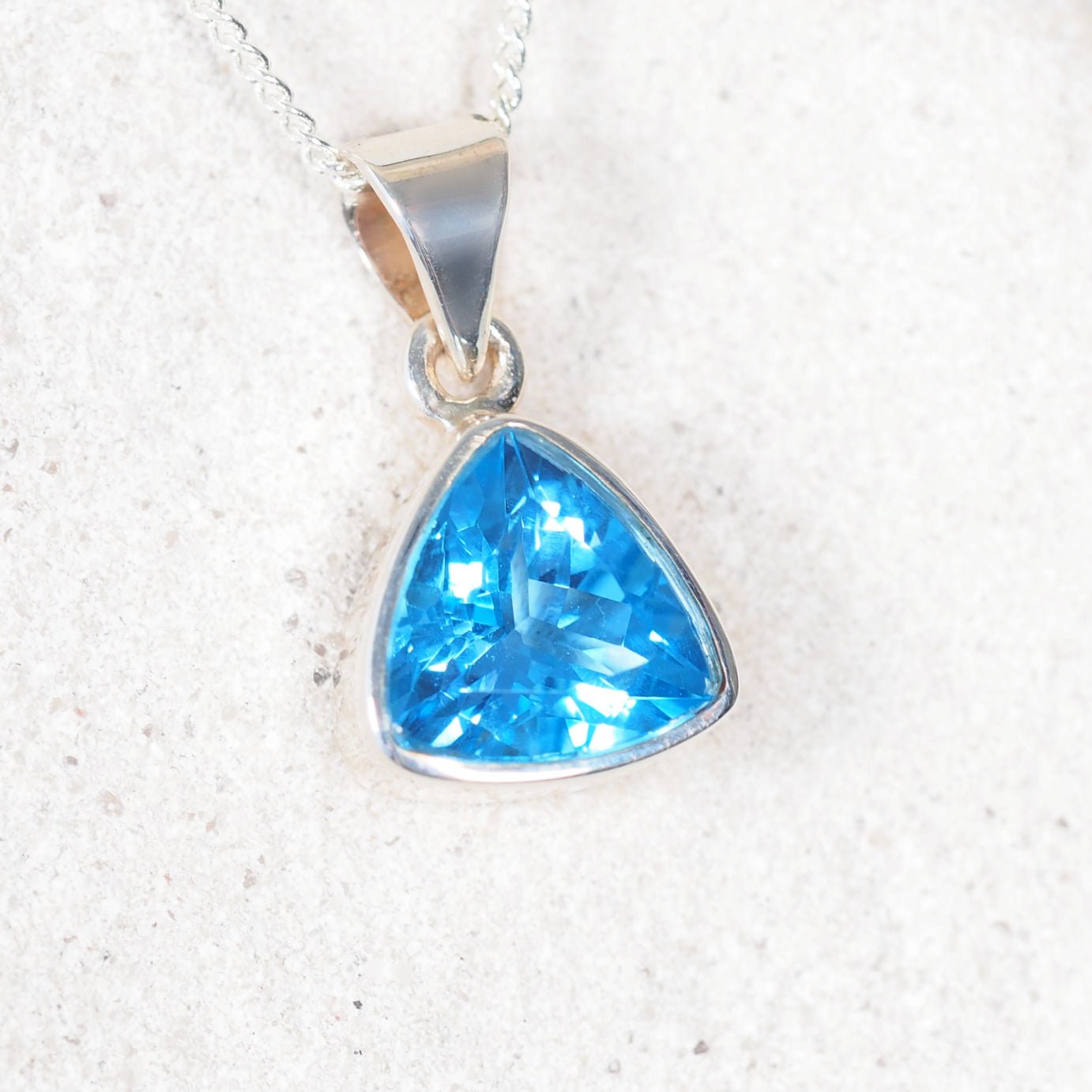 blue topaz silver pendant set against a white rock