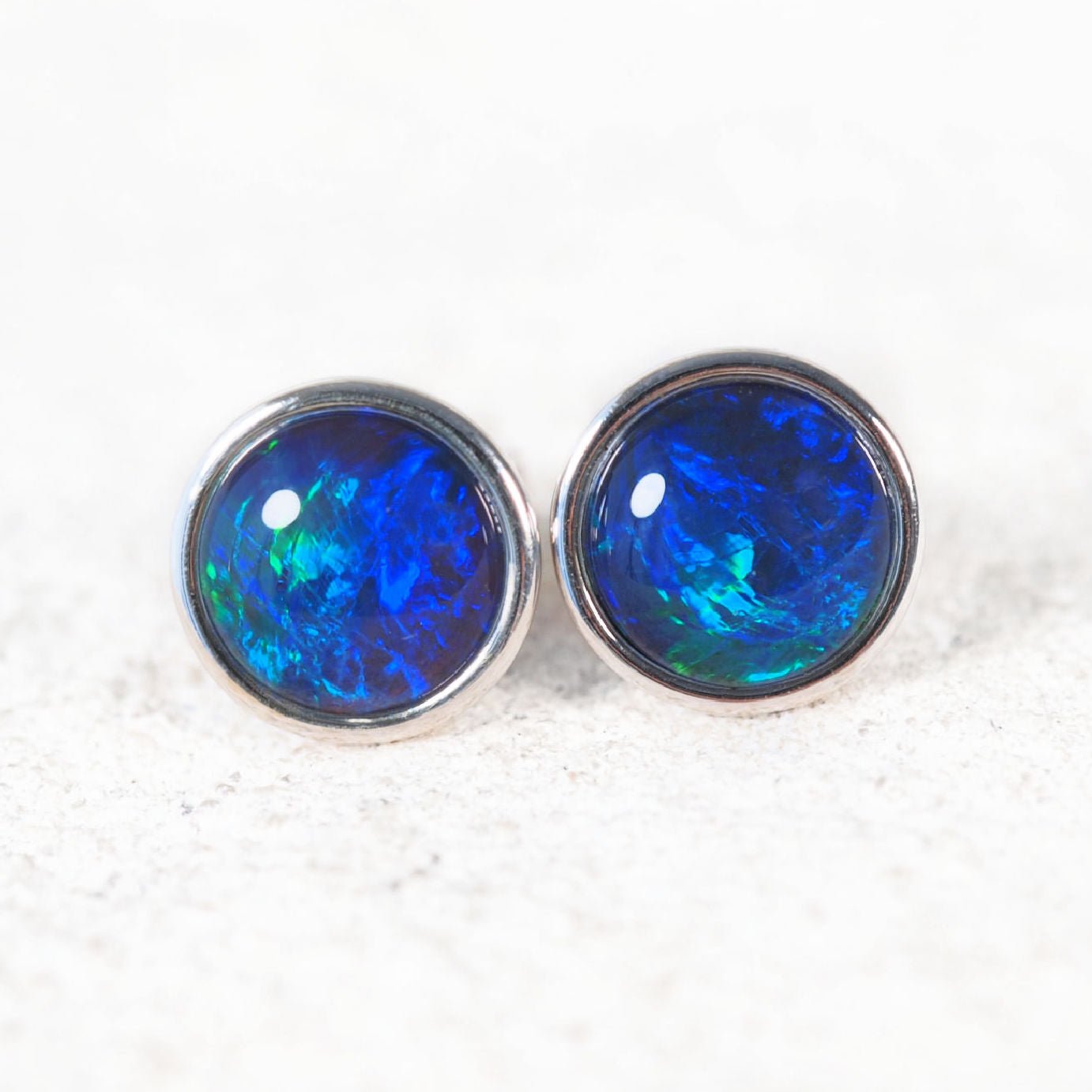 Pair of blue opal stud earrings on a white background