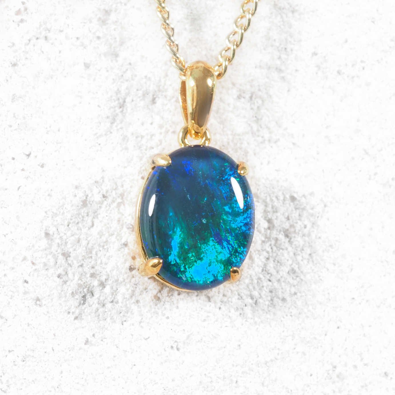 Blue opal pendant on a gold chain against a white background