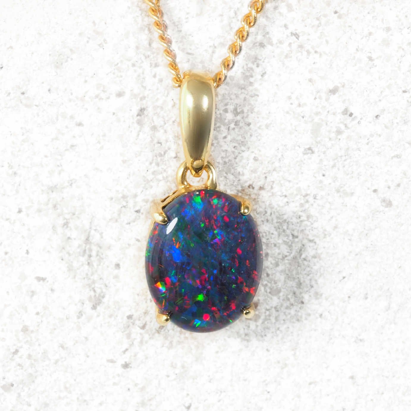 Opal pendant on a gold chain against a white background