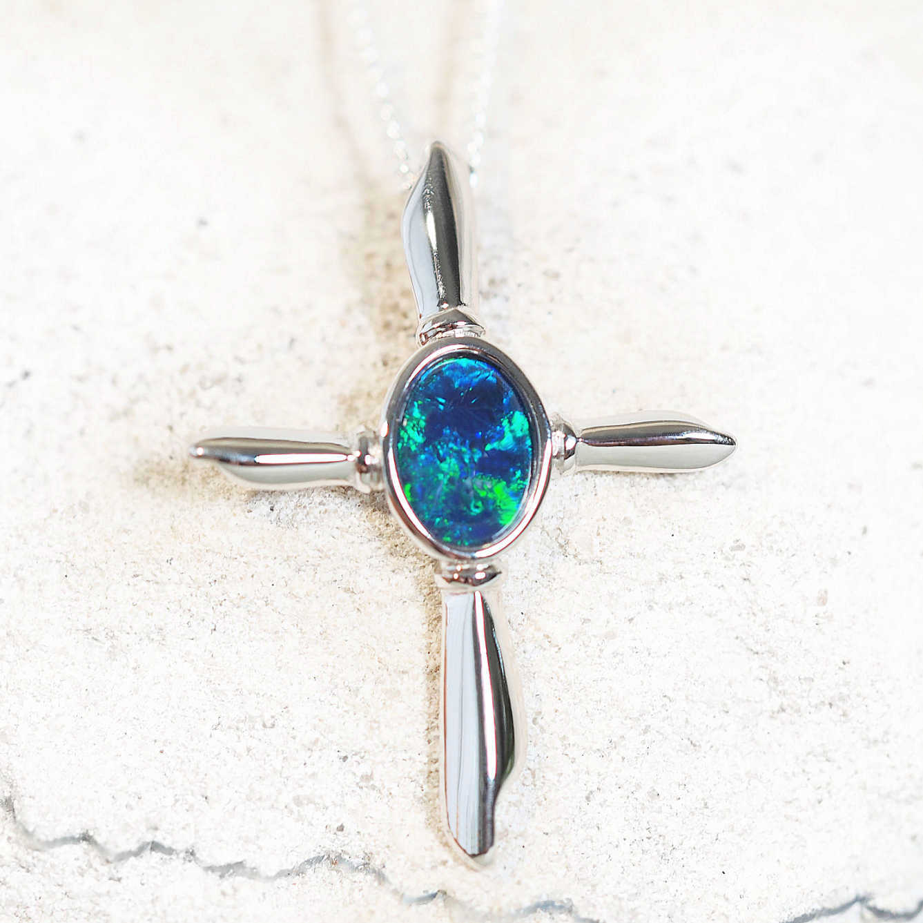 cross opal pendant set with a green and blue triplet opal stone