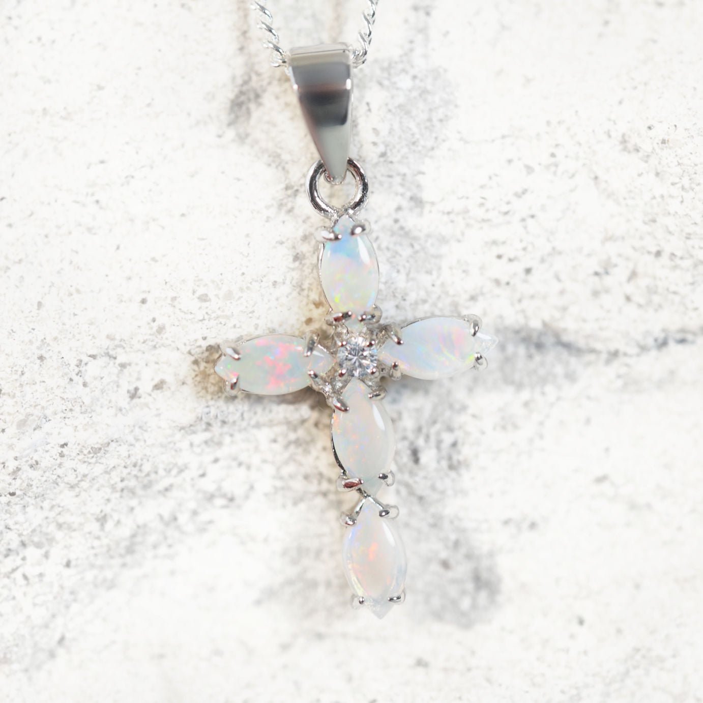 Opal cross pendant necklace on a marble background