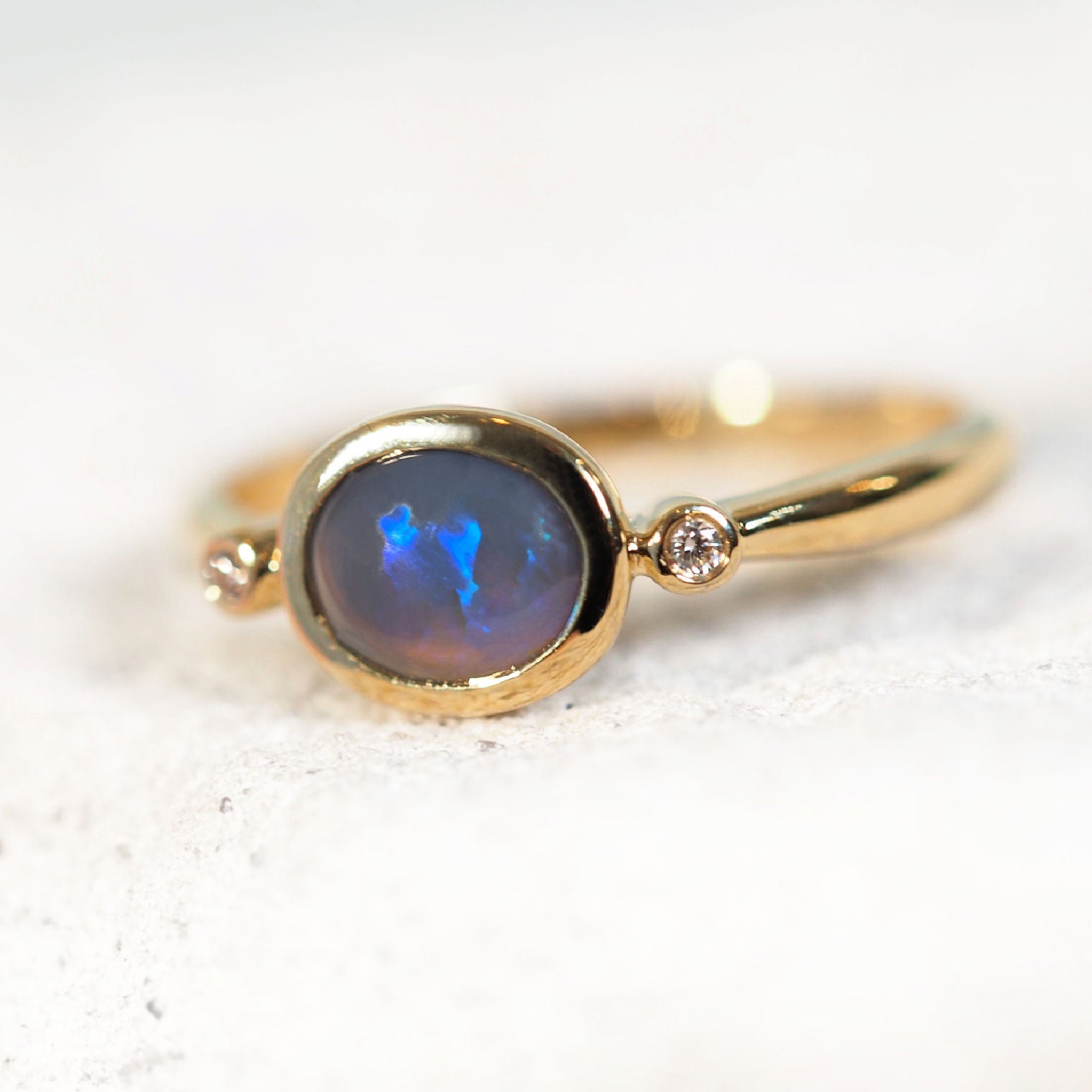Gold ring with a blue opal gemstone on a white background
