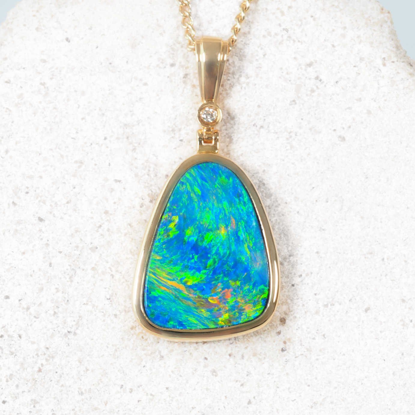 Triangular Australian doublet opal pendant in 14ct yellow gold with diamond accent