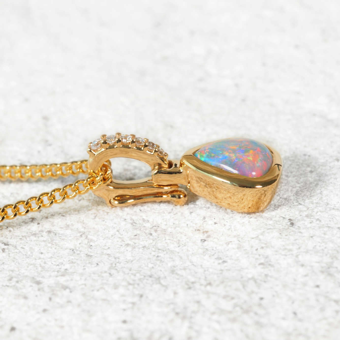 Gold necklace with an opal pendant on a textured white surface