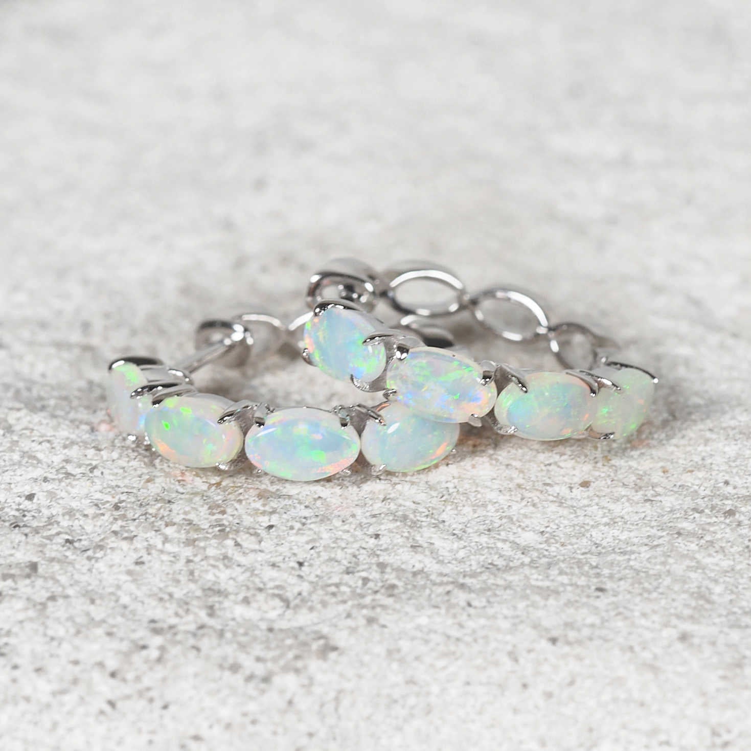 Close-up of 14ct white gold hoops featuring vivid green, blue, and pink opals