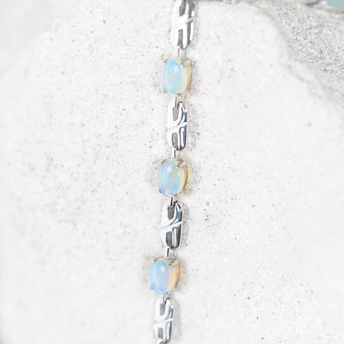 Silver bracelet with solid Australian opal stones on a textured white surface