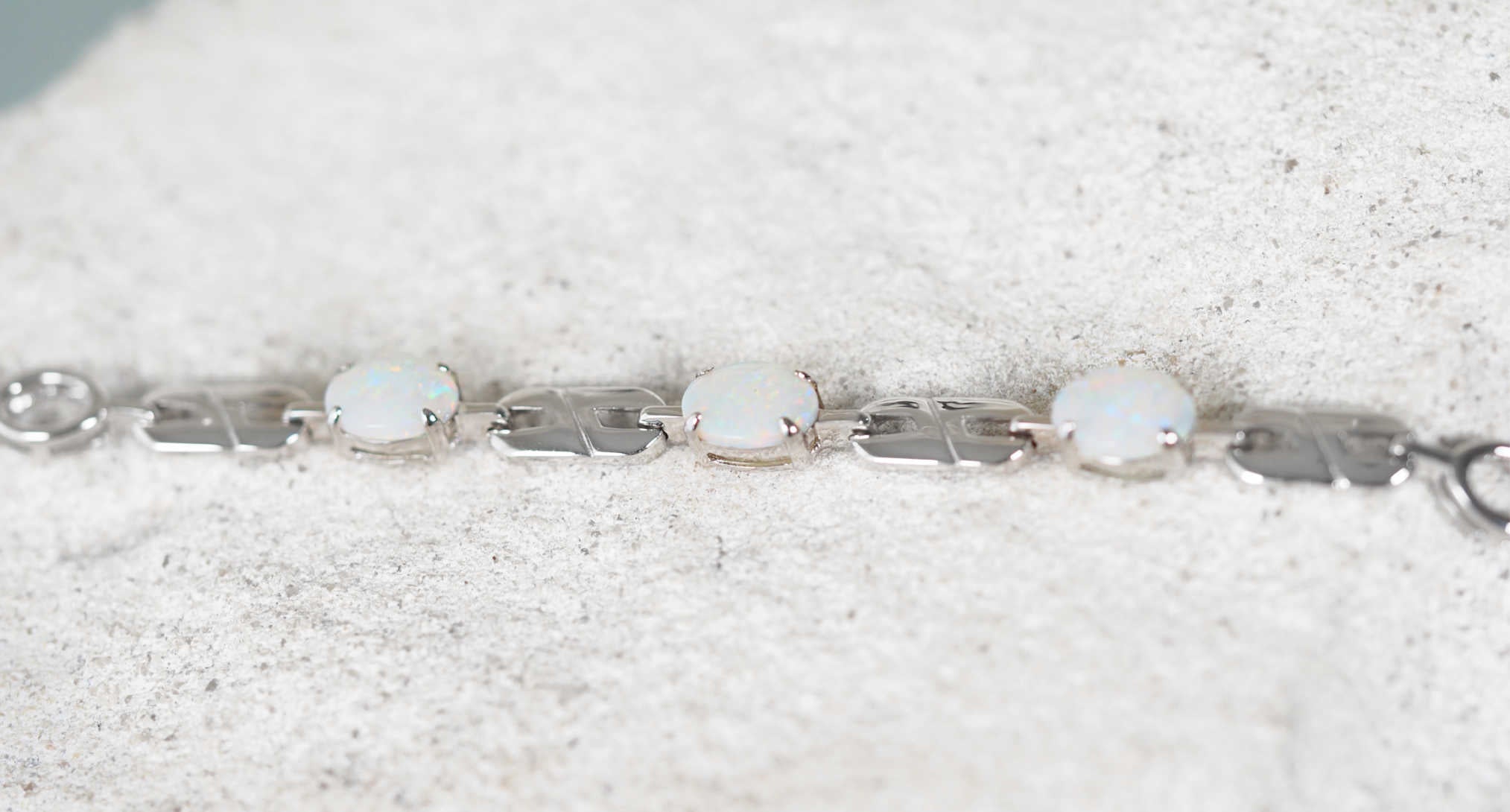 Silver bracelet with solid opal stones on a textured white surface
