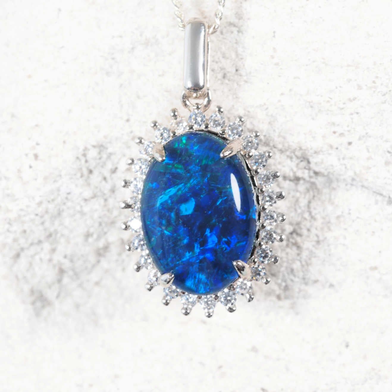 ‘Duchess Blue’ sterling silver opal pendant with claw-set oval Australian triplet opal in blue and green, surrounded by 26 sparkling cubic zirconias