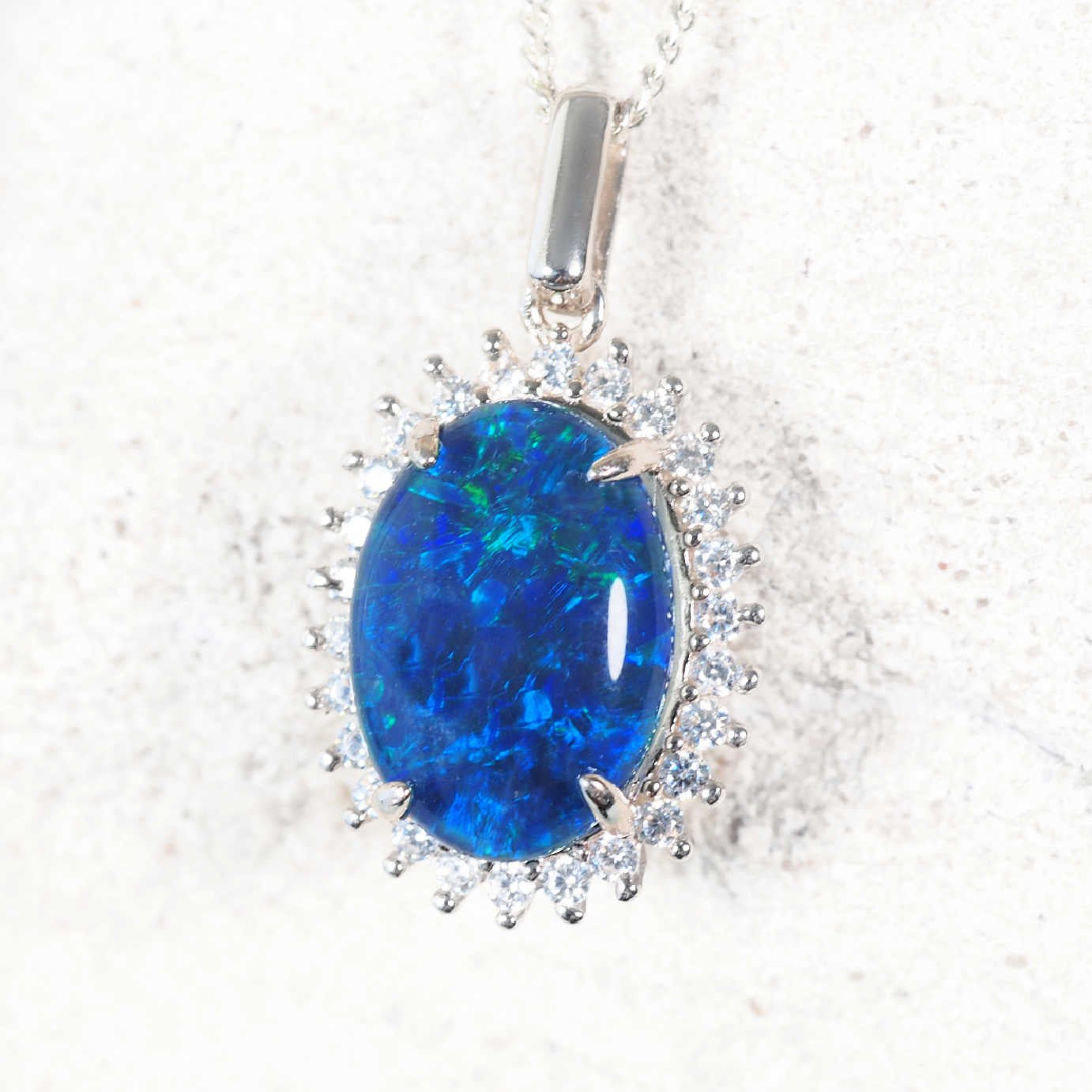 Statement sterling silver opal necklace pendant featuring oval blue and green Australian triplet opal with halo of 26 cubic zirconias