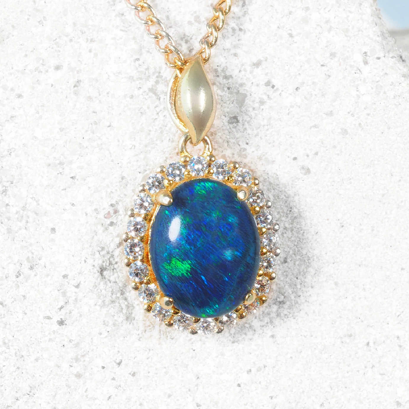 Blue-green opal pendant necklace with gold chain on a white background
