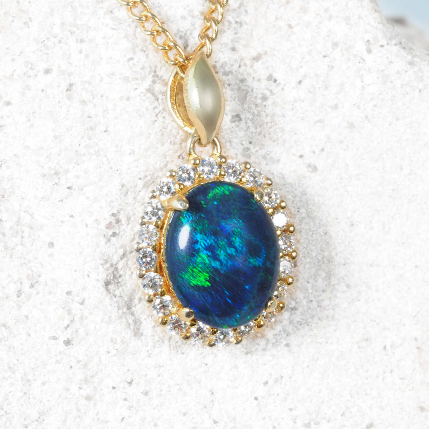Opal pendant necklace with gold chain on a white background