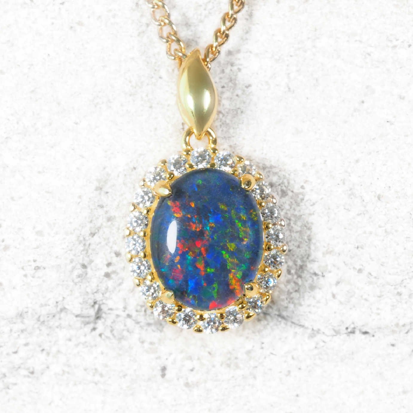 Opal pendant necklace with gold chain on a white background