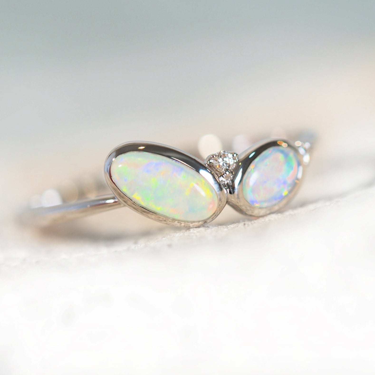 two crystal opals set in a white gold ring with diamonds