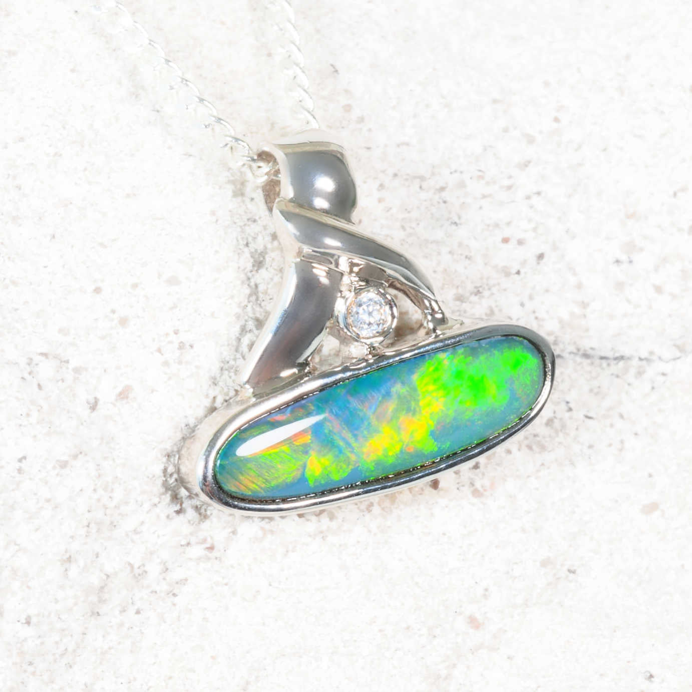 Opal pendant with silver setting on a textured white background