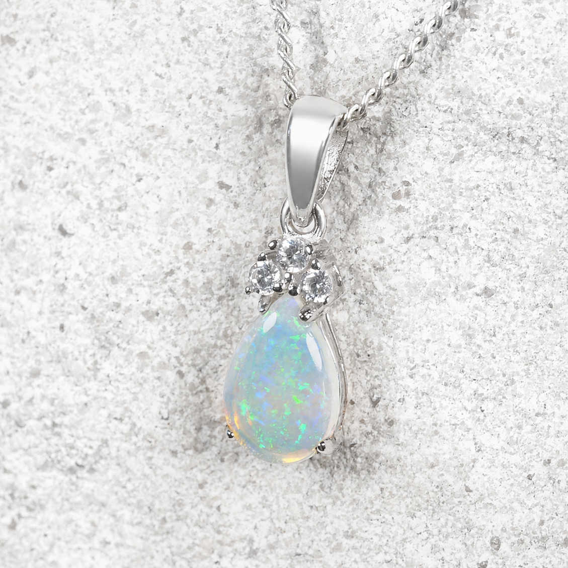 Opal pendant necklace on a textured silver background