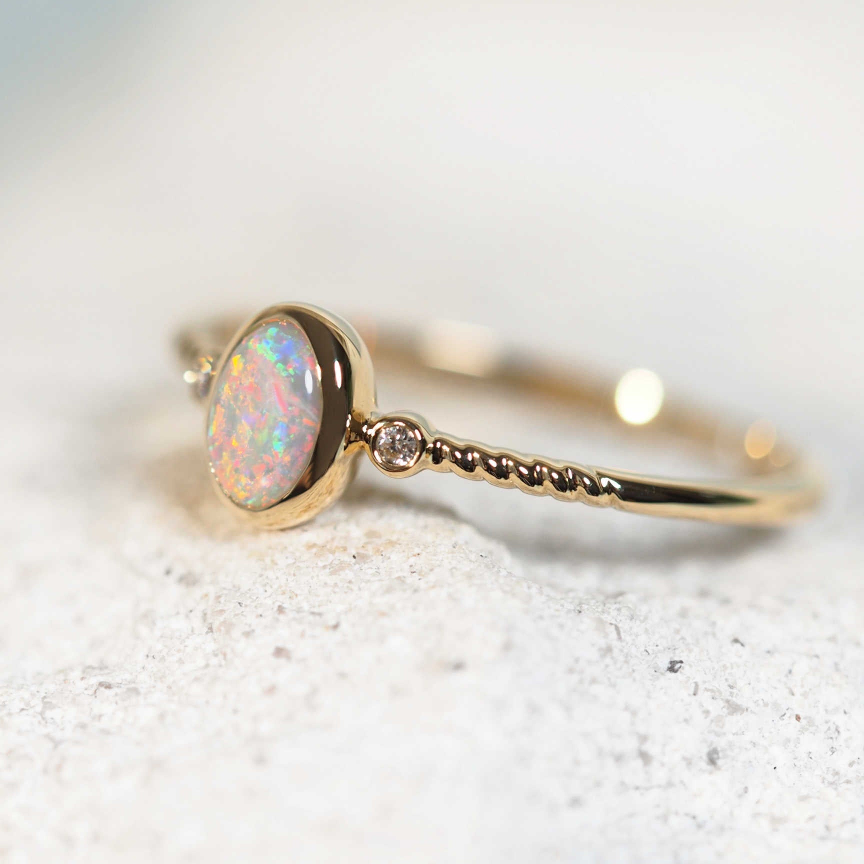 Bezel-set opal and two shoulder diamonds set in 14ct yellow gold ring

