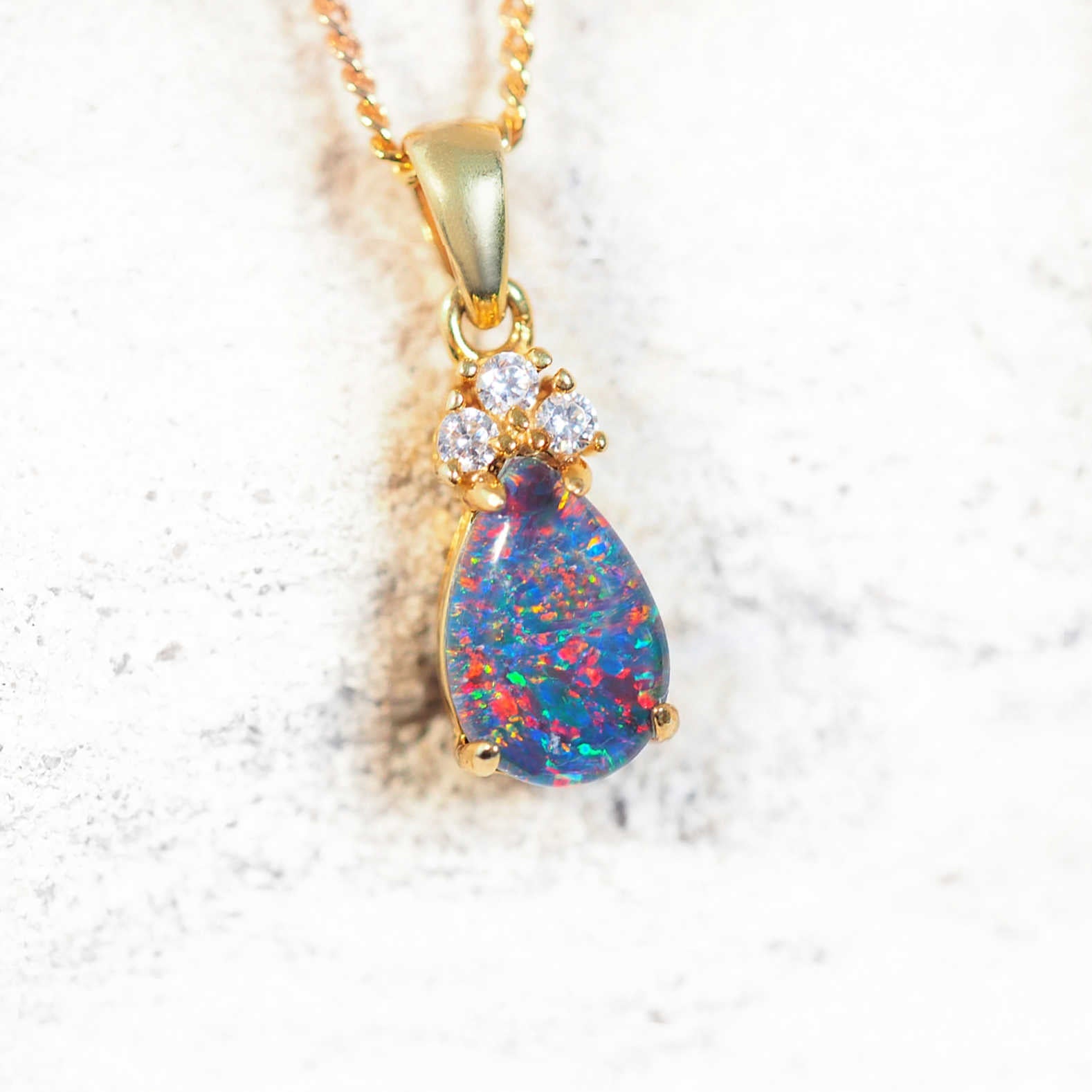 Teardrop opal pendant with multi-colour play-of-colour and three cubic zirconias