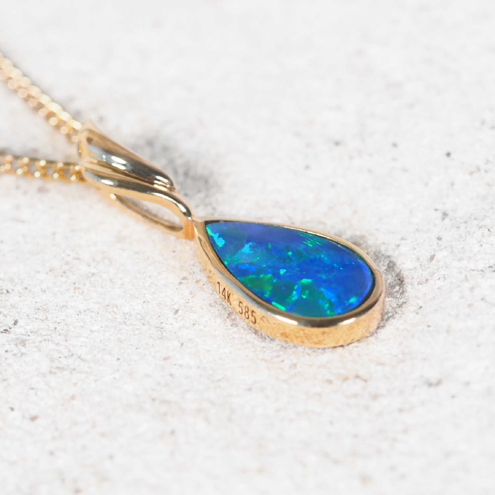 Close-up of Elisa opal pendant with bezel-set opal and gold-plated display chain