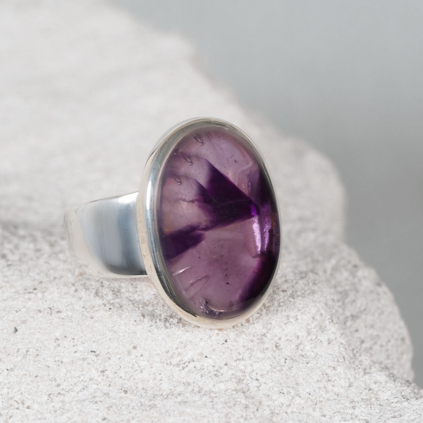Elegant silver ring, ‘Ella,’ featuring a smooth round amethyst cabochon with soft and deep purple shades