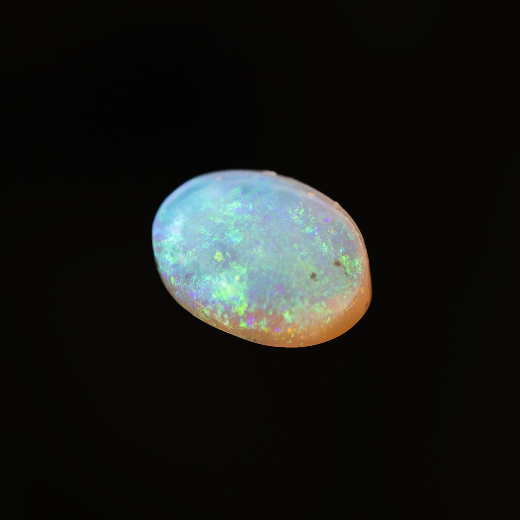 Oval-shaped Australian crystal opal gemstone showing bright green flashes