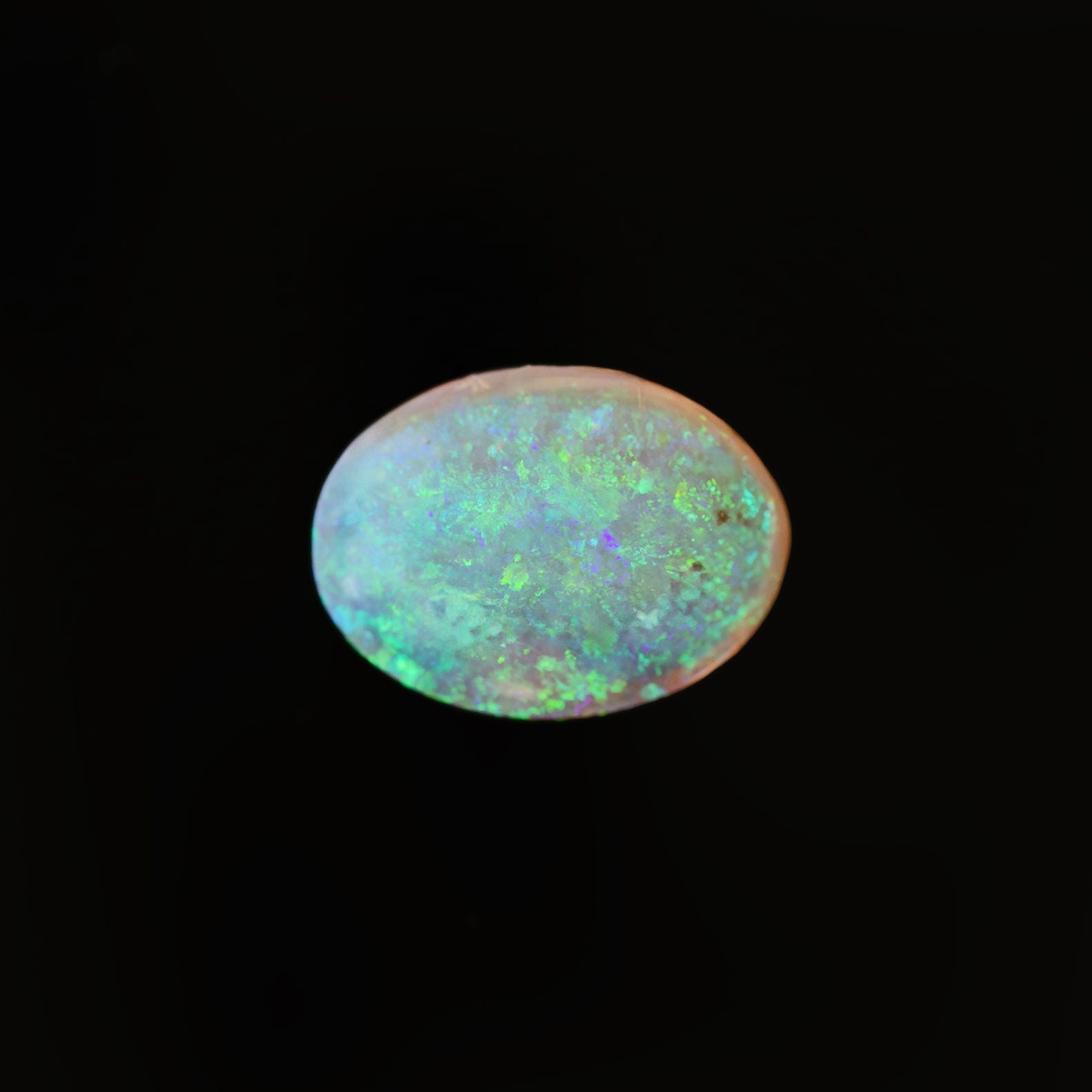 Close-up of green-speckled Lightning Ridge crystal opal in oval cut
