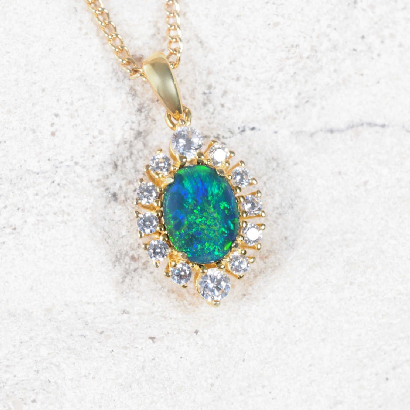 Opal pendant with gold frame and diamantes on a light background