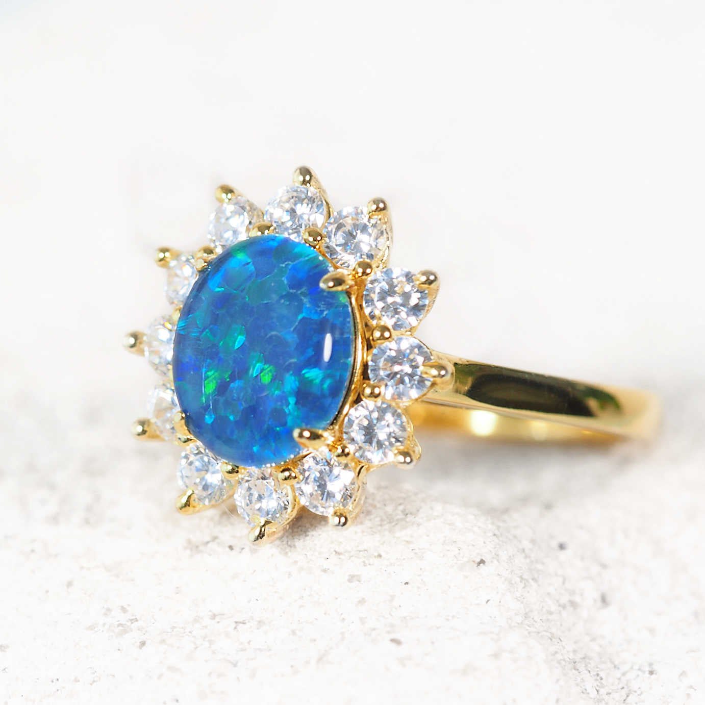 Gold ring with a blue opal stone and diamond accents on a light background