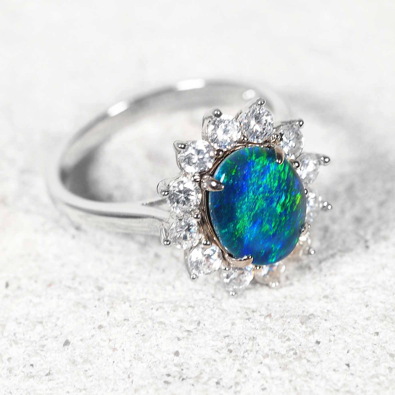 blue opal ring with a halo of crystals on a white rock